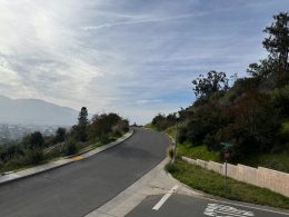 eine-geschwungene-strasse-mit-einem-schild-an-der-seite-Gpgs6YeleHs